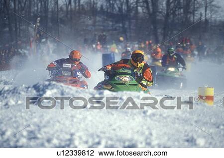 Stock Image -  snowmobile, winter, racing, Waitsfield, VT, Vermont, Two racers approaching a curve in the Snowmobile Race at the Mad River Valley Winter Carnival in Waitsfield in winter.. Fotosearch