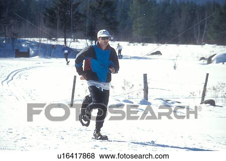 Stock Photo -  snowshoeing, winter, Waitsfield, VT, Vermont, Man participating in the Snowshoe Race at the Mad River Valley Winter Carnival in Waitsfield in winter.. Fotosearch
