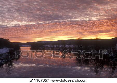 Stock Photo -  sunset, river, Vermont, VT, Reflection of colorful clouds on the Connecticut River at sunset in winter in Newbury.. Fotosearch