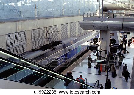 Stock Photo -  TGV, train, Paris, Charles de Gaulle, airport, France, Europe, TGV high-speed train pulls into the TGV Train Station at the Roissy/Charles de Gaulle Airport. Escalators going down to platform.. Fotosearch