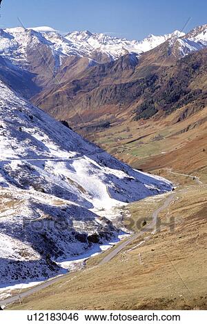 Stock Photograph -  The Pyrenees, Col du Tourmalet, Midi-Pyrenees, France, Hautes-Pyrenees, Europe, A mountain road winds down through the snow capped Pyrenees Mountains and the valley below of Col du Tourmalet.. Fotosearch