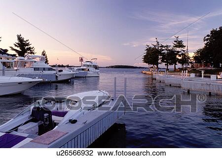 Stock Image -  Thousand Islands, Alexandria Bay, New York, St. Lawrence River, NY, Boats at a marina in Alexandria Bay along the St. Lawrence River in the evening.. Fotosearch