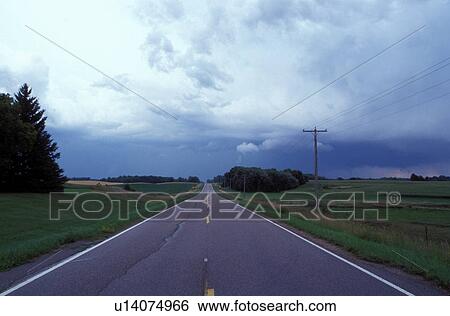 Stock Photograph -  thunderstorm, cumulus clouds, MN, Minnesota, Alexandria, Threatening thunderstorm approaching in the distance along a road in Alexandria.. Fotosearch