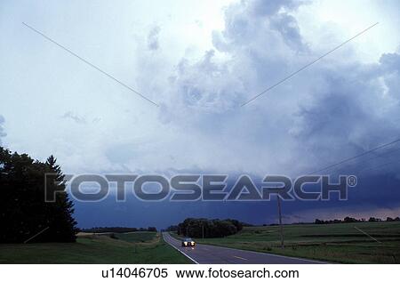 Stock Photography -  thunderstorm, cumulus clouds, MN, Minnesota, Alexandria, Threatening thunderstorm approaching along a road in Alexandria.. Fotosearch