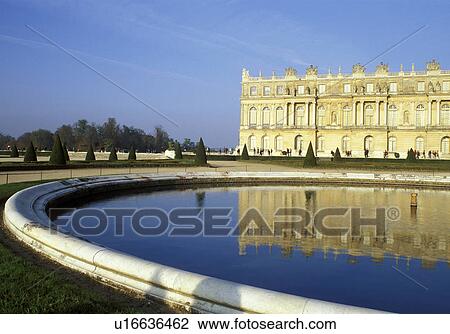 Stock Image -  Versailles, France, Ile de France, Paris, Yvelines, Europe, The palace reflects in the pool in the gardens at Chateau de Versailles.. Fotosearch