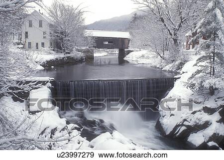 Stock Photo -  waterfall, covered bridge, river, winter, snow, Mad River Valley, Warren Covered Bridge c. 1880 crosses over the Mad River as it cascades over the snow covered wall of rocks on on a wintry day in Warren in Washington County in the state of Vermont. . Fotosearch