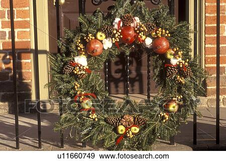 Stock Photo -  wreath, Colonial Williamsburg, Virginia, VA, Williamsburg, A wreath made of greens and fruit decorates the iron railing of the village store for Christmas in Colonial Williamsburg.. Fotosearch