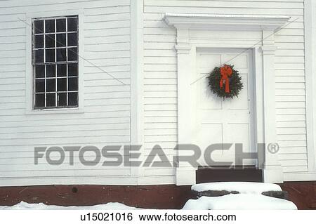 Stock Photograph -  wreath, door, white church, bow, ribbon, holiday, chapel, Christmas, winter, snow, A Christmas wreath hangs on the door of The Old Round Church (a 16-sided polygon) National Historical Landmark on a snow covered day in Richmond in Chittenden County in th. Fotosearch