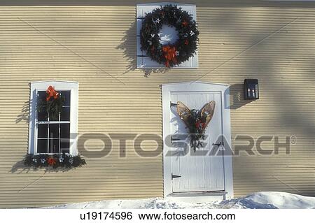 Stock Photograph -  wreaths, snowshoe, door, Christmas wreath, ribbon, bow, holiday, decorations, winter, snow, A Christmas wreath, window and wooden snowshoes decorate the outside wall of the Inn at the Round Barn Farm in Waitsfield in Mad River Valley in the state of Verm. Fotosearch