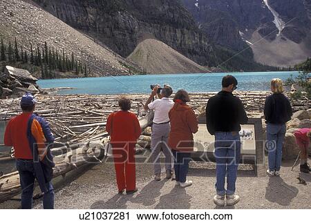 Stock Image -  Banff National Park, Canada, Alberta, Moraine Lake, Canadian Rockies, People looking out over Moraine Lake at the mountains in Banff National Park in Alberta.. Fotosearch