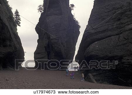 Stock Image -  Bay of Fundy, NB, Hopewell Rocks, low tide, New Brunswick, Hopewell Cape, Canada, Tourists exploring Flower Pot Rocks at low tide on the Bay of Fundy at The Rocks Provincial Park on Hopewell Cape in New Brunswick.. Fotosearch