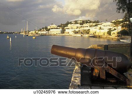 Stock Photograph -  Bermuda, St. George's Parish, Cannon overlooking St. George's Harbor at sunset in St George in Bermuda., . Fotosearch