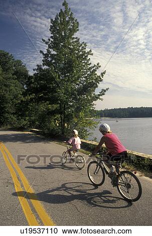 Stock Image -  biking, mother, daughter, Stone Mountain, GA, Atlanta, Georgia, Mother and eight year old daughter biking with helmets on at Georgia's Stone Mountain Park in Stone Mountain. . Fotosearch