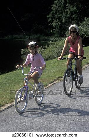 Stock Image -  biking, mother, daughter, Stone Mountain, GA, Atlanta, Georgia, Mother and eight year old daughter biking with helmets on at Georgia's Stone Mountain Park in Stone Mountain. . Fotosearch