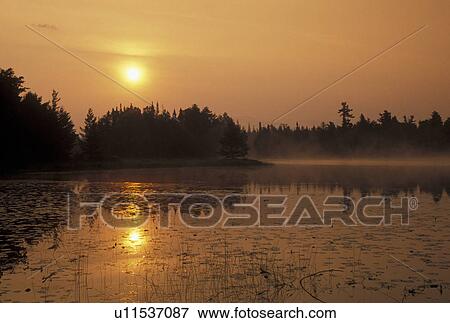 Boundary Waters, lake, sunrise, MN, Ely, Minnesota, Sunrise on Lake One in the Boundary Waters Canoe Area Wilderness in Minnesota. The chain of lakes and rivers serve as the Border between USA and Canada. View Large Photo Image Stock Photo - Boundary Waters, lake, sunrise, MN, Ely, Minnesota, Sunrise on Lake One in the Boundary Waters Canoe Area Wilderness in Minnesota. The chain of lakes and rivers serve as the Border between USA and Canada.. Fotosearch