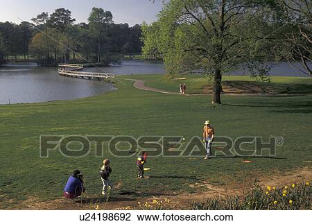 Stock Image -  Callaway Gardens, Pine Mountain, Georgia, GA, Family playing baseball next to Mountain Creek Lake at Callaway Gardens in Pine Mountain.. Fotosearch