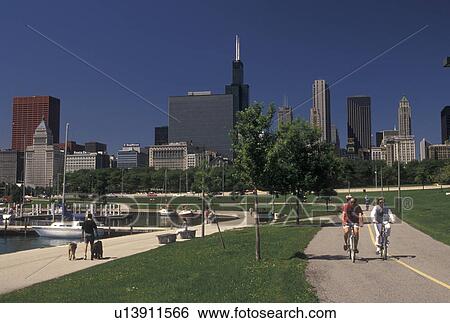 Stock Photograph -  Chicago, IL, Illinois, Chicago Harbor, People biking on Lakefront Trail on the waterfront of Lake Michigan at Grant Park in Chicago.. Fotosearch