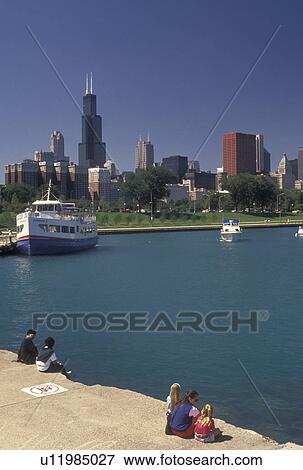 Stock Photo -  Chicago, IL, Lake Michigan, Illinois, People watching a sightseeing tour boat in the Chicago Harbor from Grant Park with a view of the downtown skyline of Chicago. . Fotosearch