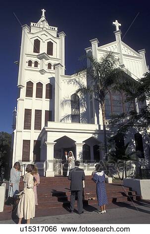 Stock Photograph -  church, wedding, Florida Keys, Key West, FL, Gulf of Mexico, Florida, Atlantic Ocean, Bridge and groom stand outside St. Paul's Church posing for pictures in Key West.. Fotosearch