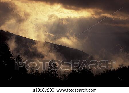 Stock Image -  clouds, fog, sun rays, Blue Ridge, NC, North Carolina, Scenic view of the sunrays breaking through the clouds over the mountains in Pisgah National Forest in North Carolina.. Fotosearch
