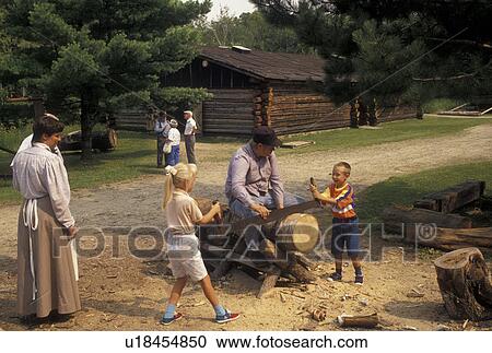 Stock Image -  forestry, logging, Grand Rapids, MN, Minnesota, Interpreter teaches two children how to use a two man saw at the 19th-century Logging Camp at the Forest History Center in Grand Rapids.. Fotosearch