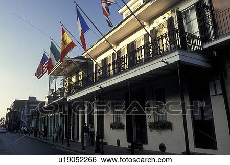 Stock Photograph -  French Quarter, New Orleans, LA, Louisiana, Flags outside a two story building with a cast iron balcony in the French Quarter in New Orleans. . Fotosearch