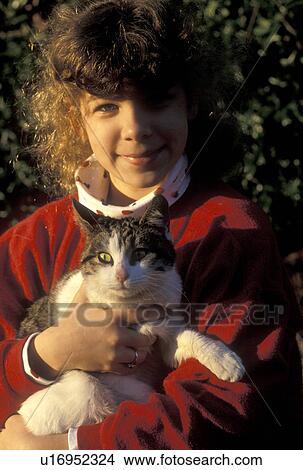 Picture -  girl, cat, Young nine year old girl with red sweatshirt cuddles her cat in her arms in Atlanta, GA.. Fotosearch
