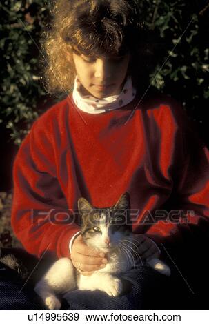 Stock Photo -  girl, cat, Young nine year old girl with red sweatshirt holds her cat in her arms in Atlanta, GA.. Fotosearch