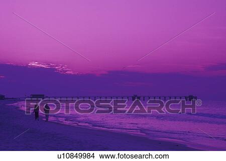 Picture -  Gulf Shores, AL, Alabama, Gulf of Mexico, Couple walking along the beach at sunrise at Gulf Shores along the Gulf of Mexico.. Fotosearch