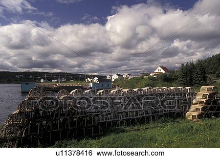 Stock Photograph -  lobster traps, Cape Breton, fishing village, Nova Scotia, NS, Canada, Atlantic Ocean, Lobster traps stack on the shore of Louisbourg Harbor on Cape Breton Island in Nova Scotia. . Fotosearch