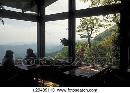 Stock Image -  lodge, restaurant, NC, Blue Ridge Parkway, Pisgah National Forest, North Carolina, People eating at the restaurant at Pisgah Lodge with scenic view of the mountains in the background in North Carolina.. Fotosearch