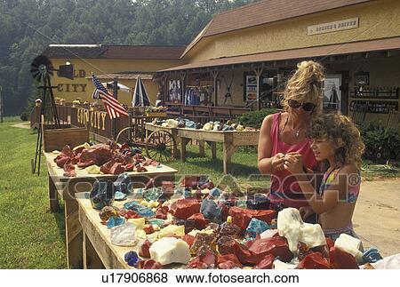 Stock Photo -  mine, NC, North Carolina, Mother and 8 year old daughter looking at colorful glass stones at the Gold City Gem Mine gift shop in North Carolina.. Fotosearch