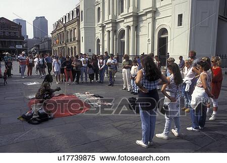 Stock Photography -  New Orleans, LA, French Quarter, St. Louis Cathedral, Louisiana, Street artist entertains a crowd of people outside the Saint Louis Cathedral at Jackson Square in the French Quarter in New Orleans. . Fotosearch
