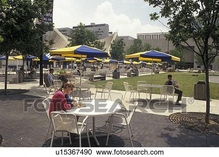 Stock Image -  outdoor cafT, Kansas City, MO, Missouri, Woman reading a book at a table at the outdoor cafT at Crown Center Complex in Kansas City.. Fotosearch