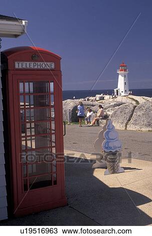 Stock Image -  red telephone booth, lighthouse, Peggy's Cove, fishing village, Nova Scotia, NS, Canada, Atlantic Ocean, A red telephone booth stands in the foreground of the old lighthouse in Peggy's Cove in Nova Scotia. . Fotosearch