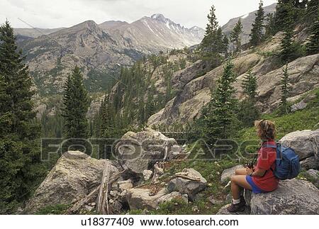 Rocky Mountain National Park, CO, Colorado, Rocky Mts Woman sitting on a rock looking at the scenic view of the alpine mountains in Rocky Mountain Nat'l Park. View Large Photo Image Stock Photo - Rocky Mountain National Park, CO, Colorado, Rocky Mts Woman sitting on a rock looking at the scenic view of the alpine mountains in Rocky Mountain Nat'l Park.. Fotosearch