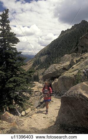 Stock Image -  Rocky Mountain National Park, woman, hiking, Rocky Mountains, CO, Colorado, Woman hiking with a backpack on a hiking trail in Rocky Mountain Nat'l Park.. Fotosearch