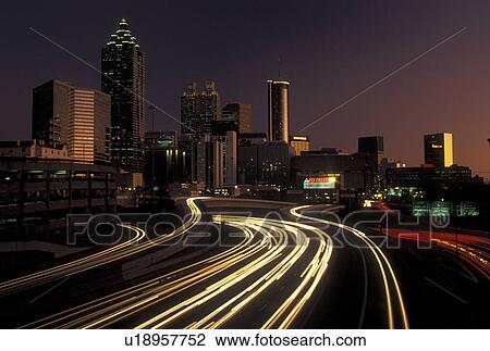 Stock Image -  skyline, highway, Atlanta, GA, Georgia, Traffic lights streak on I-75/I-85 at sunset and view of the skyline of downtown Atlanta.. Fotosearch