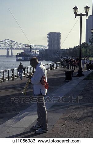 Stock Image -  street musician, jazz New Orleans, Mississippi River, Riverfront Park, LA, waterfront, Louisiana, A street musician plays his instrument on Waldenberg Riverfront Park along the Mississippi River in New Orleans. . Fotosearch