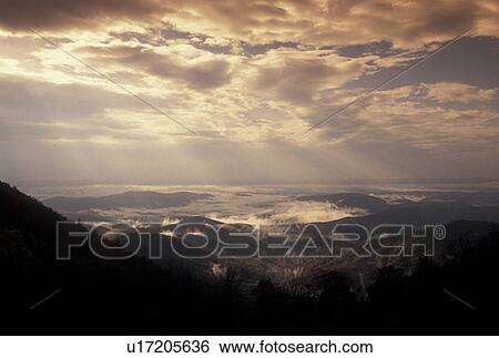 Stock Photograph -  sunrays, mountains, Blue Ridge, NC, North Carolina, Scenic view of sun rays through the clouds over the mountains from the Blue Ridge Parkway in autumn in North Carolina.. Fotosearch