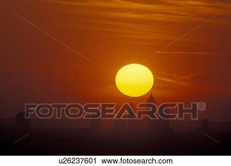 Stock Image -  sunset, Atlanta, GA, Georgia, The big yellow sun sets behind the Atlanta skyline from Stone Mountain.. Fotosearch