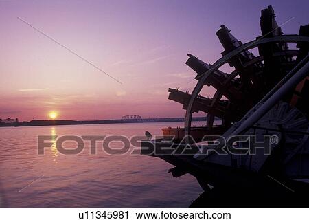 Stock Image -  sunset, Louisville, KY, riverboat, Kentucky, Ohio River, Silhouette of the paddle wheel on the Belle of Louisville Riverboat docked along the Ohio River at sunset. . Fotosearch