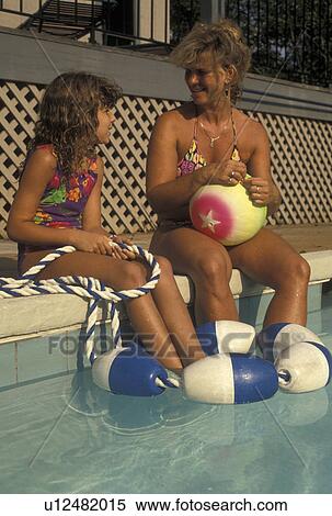 Stock Photography -  swimming pool, mother, daughter, GA, Atlanta, Georgia, Mother and eight year old daughter talk together while sitting on the side of a pool in Atlanta. . Fotosearch
