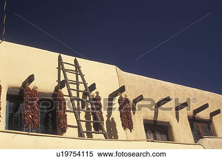 Stock Photography -  Taos, NM, New Mexico, Clusters of chili peppers drying outside an adobe style building in the village of Taos.. Fotosearch