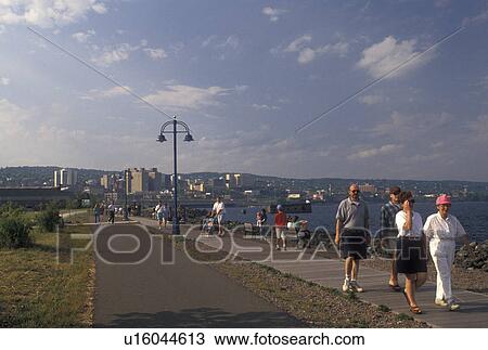 Stock Image -  waterfront, boardwalk, Duluth, MN, Minnesota, Lake Superior, People walk on the boardwalk at Downtown Lakewalk along Lake Superior in Duluth.. Fotosearch
