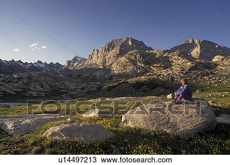 woman hiker, Wind River Range, hiking, Bridger-Teton National Forest, WY, Wyoming, Woman sitting on a large boulder in Titcomb Basin looking at the scenic view of the Wind River Range Mountains in the Bridger-Teton Nat'l Forest in Wyoming. View Large Photo Image Stock Image - woman hiker, Wind River Range, hiking, Bridger-Teton National Forest, WY, Wyoming, Woman sitting on a large boulder in Titcomb Basin looking at the scenic view of the Wind River Range Mountains in the Bridger-Teton Nat'l Forest in Wyoming.. Fotosearch