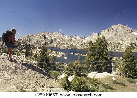 Stock Photo -  woman hiker, Wind River Range, hiking, Bridger-Teton National Forest, WY, Wyoming, Woman backpacker looking at the scenic view of Island Lake in the Wind River Range Mountains in the Bridger-Teton Nat'l Forest in Wyoming.. Fotosearch