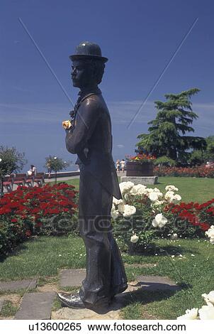 Charlie Chaplin, Switzerland, Vevey, Lake Geneva, Vaud, Statue of Charlie Chaplin holding a pink rose at the lakefront park along Lac Leman in Vevey in the Canton of Vaud. He is surrounded by beautiful red and white flowers. View Large Photo Image Stock Photography - Charlie Chaplin, Switzerland, Vevey, Lake Geneva, Vaud, Statue of Charlie Chaplin holding a pink rose at the lakefront park along Lac Leman in Vevey in the Canton of Vaud. He is surrounded by beautiful red and white flowers.. Fotosearch