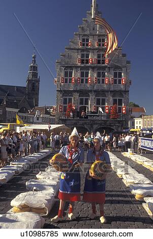 Stock Photography -  cheese market, Gouda, Holland, Netherlands, Zuid-Holland, Europe, Young women dressed in authentic costumes hold wheels of gouda cheese at the Cheese Market outside Town Hall on Cheese Market Day in downtown Gouda.. Fotosearch