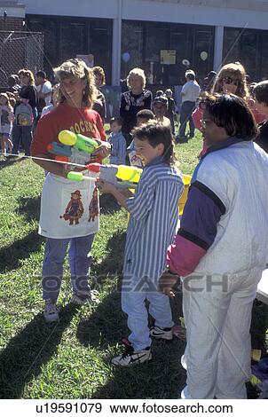 festival, school, Atlanta, GA, Georgia, Boy shoots water gun as people look on at Brockett Elementary School Fall Festival in Tucker. View Large Photo Image Stock Photo - festival, school, Atlanta, GA, Georgia, Boy shoots water gun as people look on at Brockett Elementary School Fall Festival in Tucker.. Fotosearch